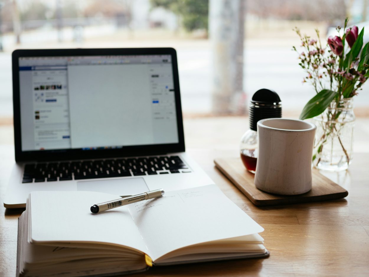 A desk with laptop, notebook and teacup