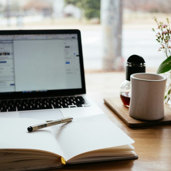 A desk with laptop, notebook and teacup